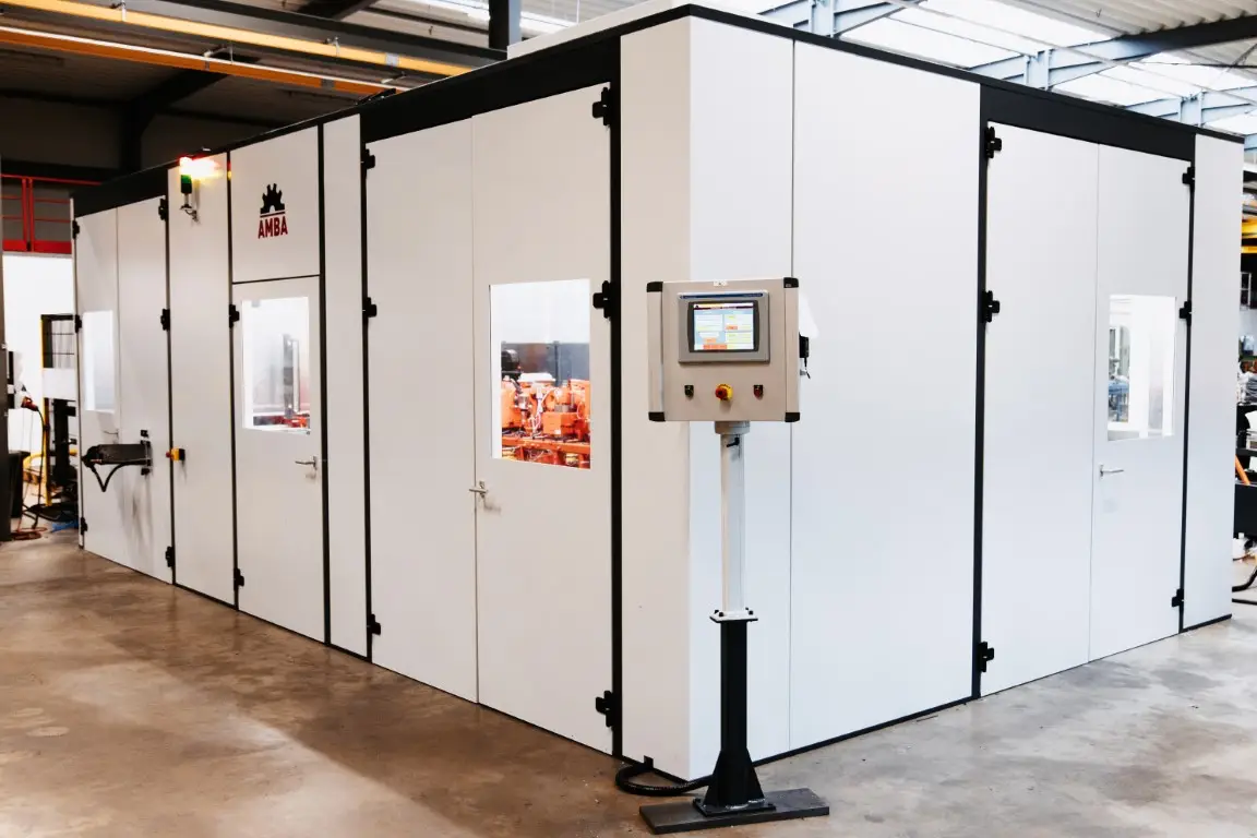 Machine protection and noise control booth in a factory, with a touchscreen control panel on a stand in the foreground