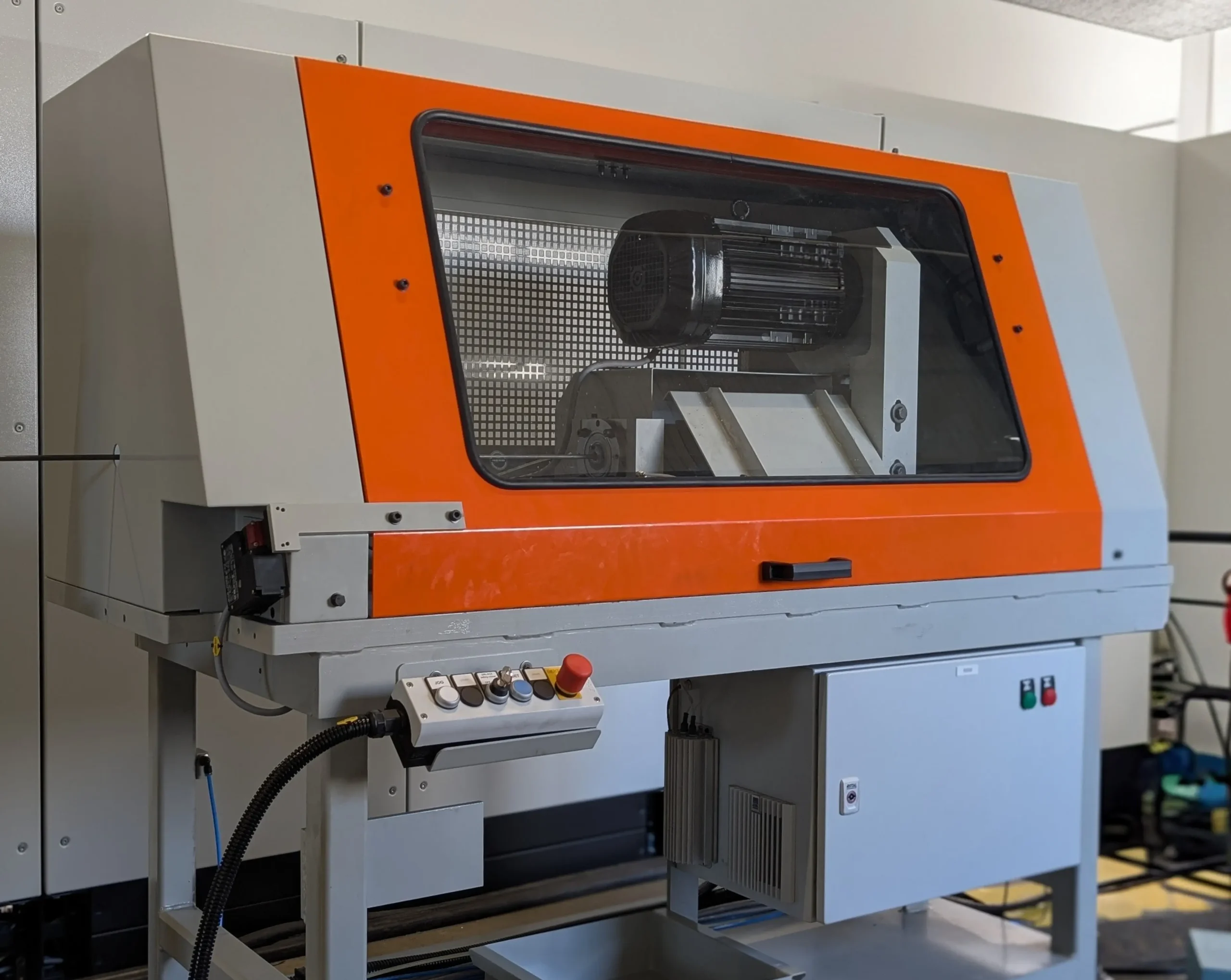 Rotierender Richtapparat zum Richten von Draht mit einer orangefarbenen Fronttür; im Inneren sind mechanische Komponenten. Der Richtapparat ist ein Beispiel für die Maschinenperipherie und Zubehör von AMBA