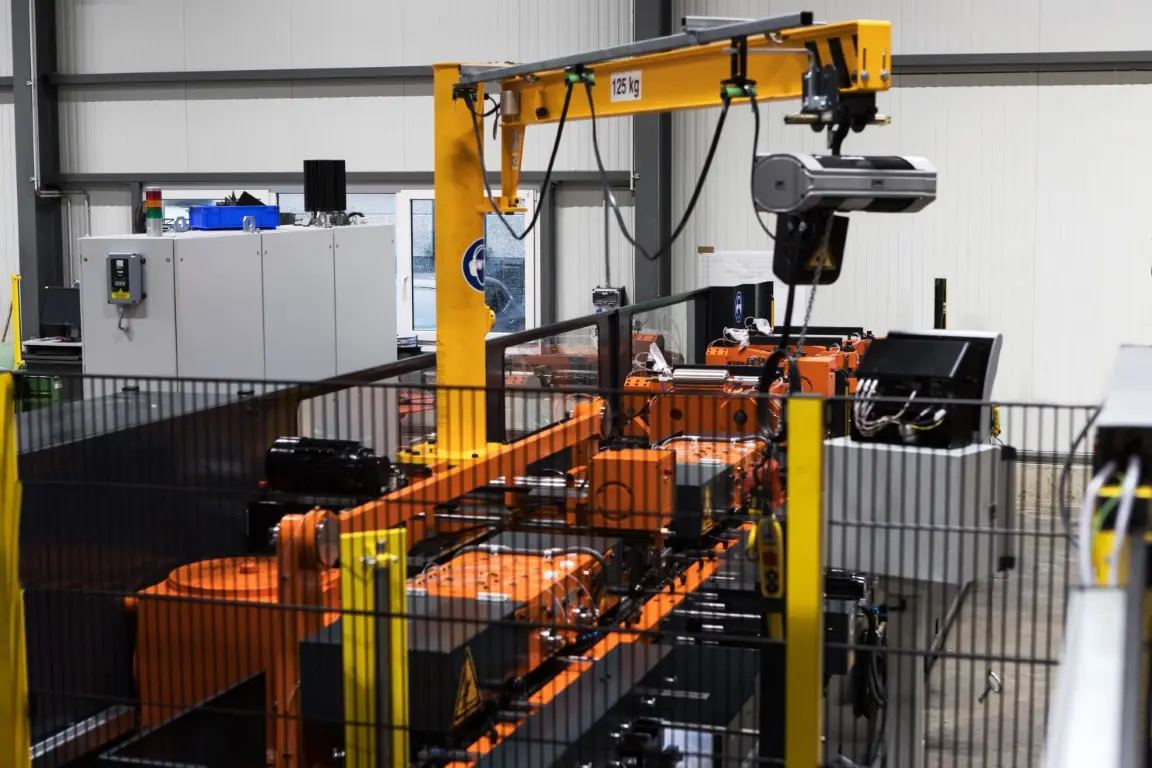 An orange-colored swivel crane for changing heavy threading tools is mounted on a screw machine