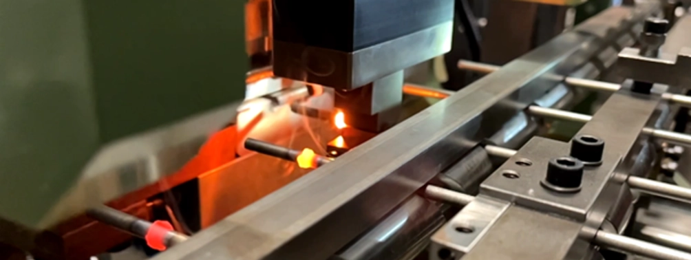 Close-up of an AMBA machine for hot forming bi-metal screws with inductively heated screw blanks.